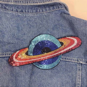 Saturnus silitettävä kangasmerkki farkkutakissa.